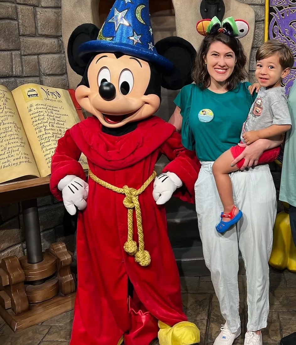 Carolina Sant'Anna e uma criança ao lado do Mickey Feiticeiro no Hollywood Studios