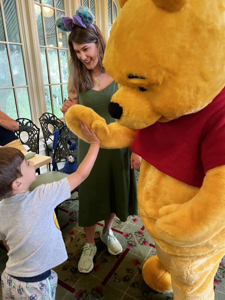 Carolina e uma criança conhecendo o Ursinho Pooh no café da manhã com personagens
